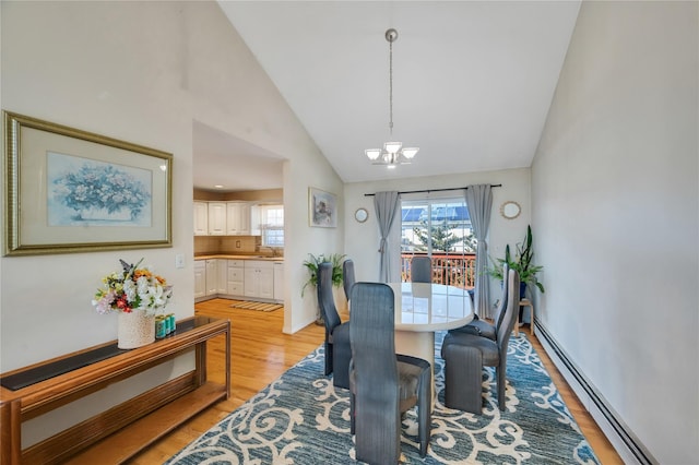 dining area featuring a notable chandelier, light wood-style floors, plenty of natural light, and baseboard heating