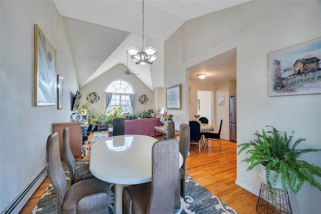 dining room with ceiling fan with notable chandelier, vaulted ceiling, light wood-style floors, and baseboard heating