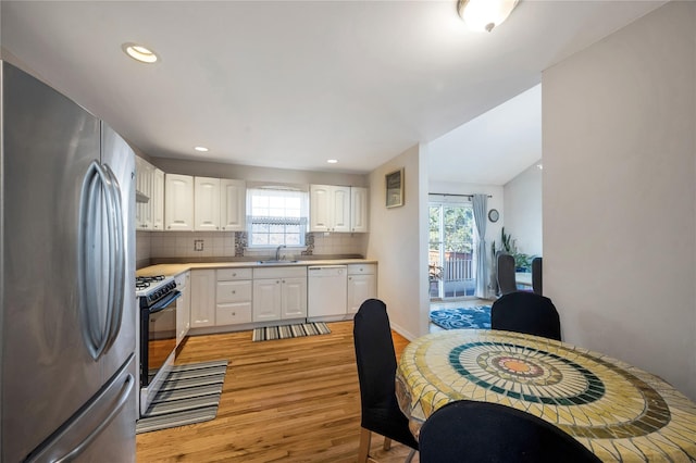 kitchen with tasteful backsplash, range with gas cooktop, dishwasher, freestanding refrigerator, and a sink