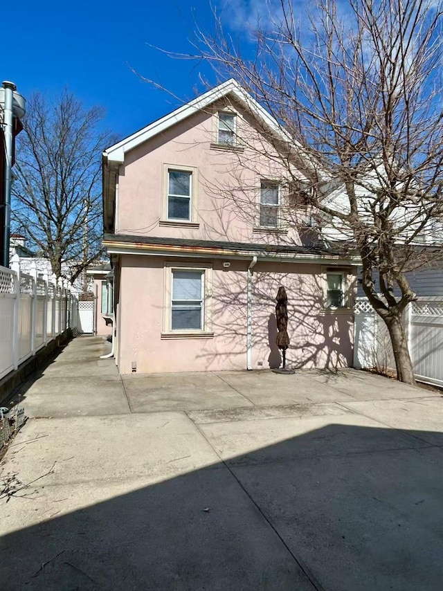 back of property with stucco siding, a patio, and fence