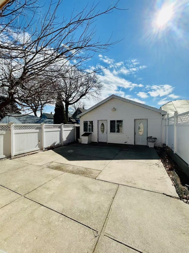 exterior space with concrete driveway, a fenced backyard, and a patio