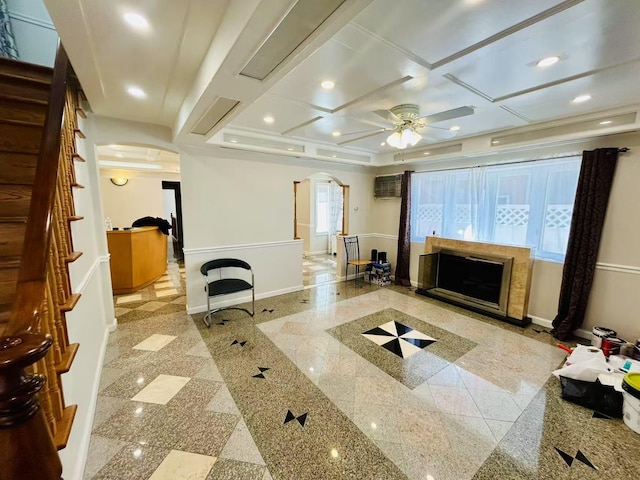 living area featuring baseboards, coffered ceiling, granite finish floor, recessed lighting, and arched walkways