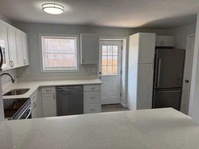 kitchen with stainless steel electric stove, freestanding refrigerator, a sink, light countertops, and dishwasher