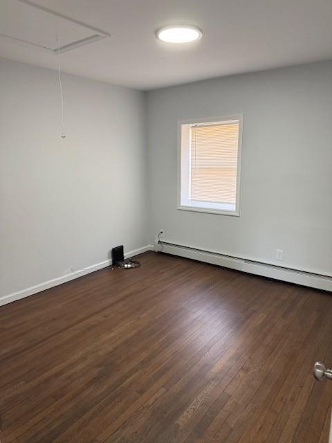 spare room featuring attic access, dark wood-style floors, baseboards, and baseboard heating