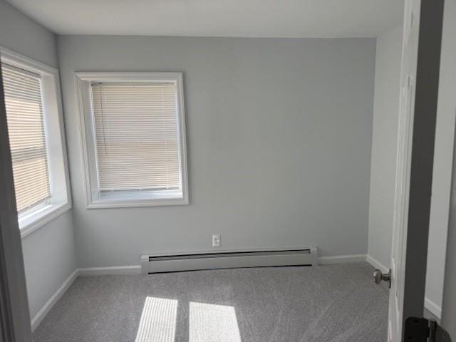 unfurnished room featuring a baseboard heating unit, baseboards, a healthy amount of sunlight, and carpet flooring