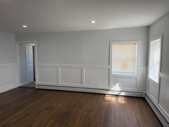 empty room featuring recessed lighting, baseboard heating, and dark wood finished floors