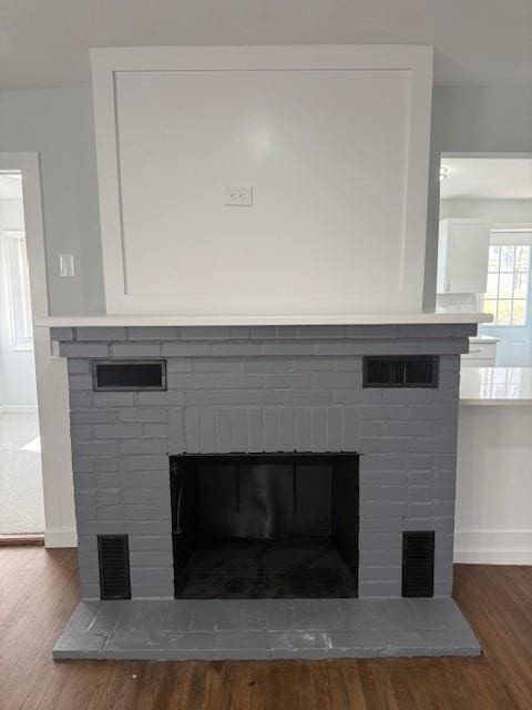 room details featuring wood finished floors, a fireplace, visible vents, and baseboards