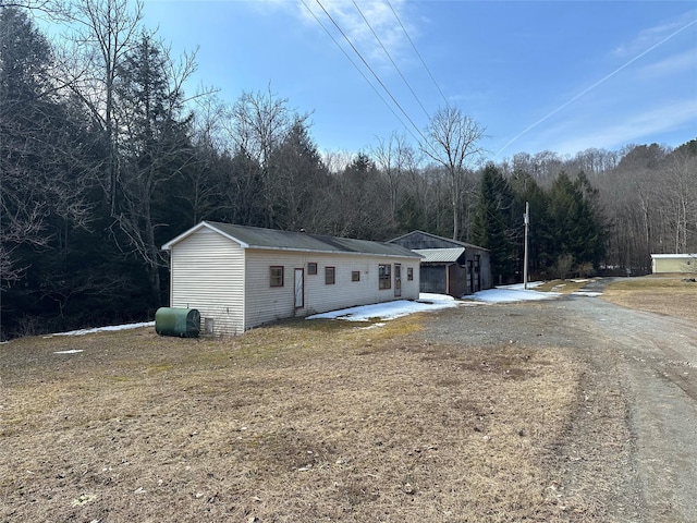 ranch-style home with a patio, a wooded view, and heating fuel