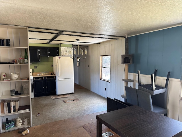 kitchen featuring hanging light fixtures, open shelves, freestanding refrigerator, and dark cabinets