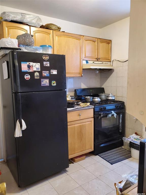 kitchen featuring black appliances, light tile patterned floors, tile walls, and under cabinet range hood