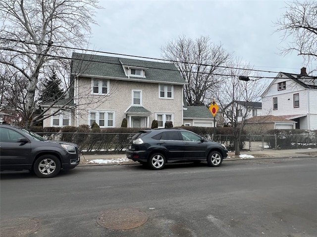 view of front of property featuring a residential view, a shingled roof, and fence