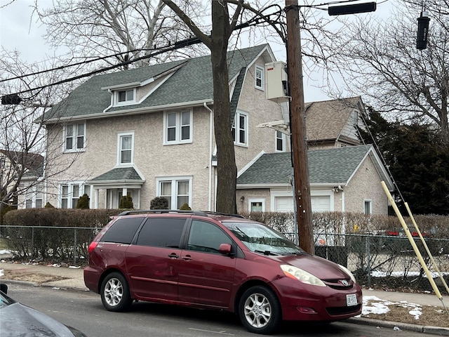 view of front of property featuring stucco siding, roof with shingles, and fence