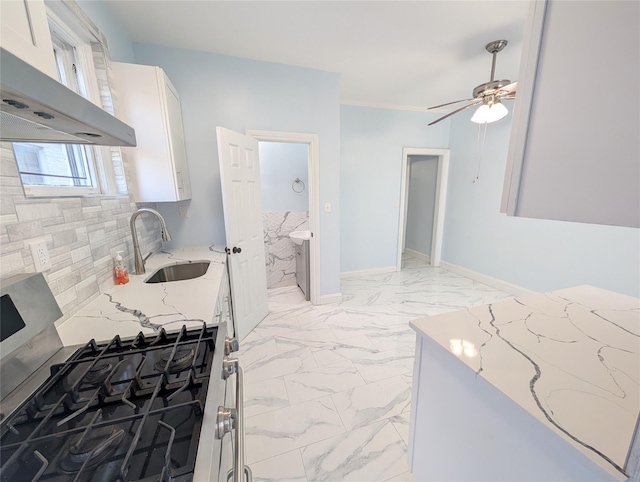 kitchen featuring wall chimney range hood, light stone countertops, marble finish floor, gas stove, and a sink