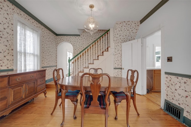 dining room featuring wallpapered walls, crown molding, visible vents, and light wood-type flooring