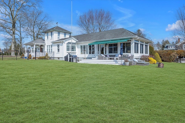 rear view of house with fence, a yard, roof with shingles, a sunroom, and a patio area