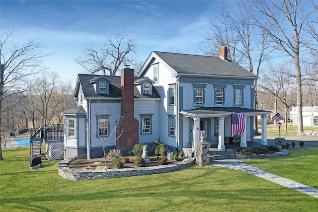 view of front of house featuring a front lawn, a porch, a chimney, and roof with shingles