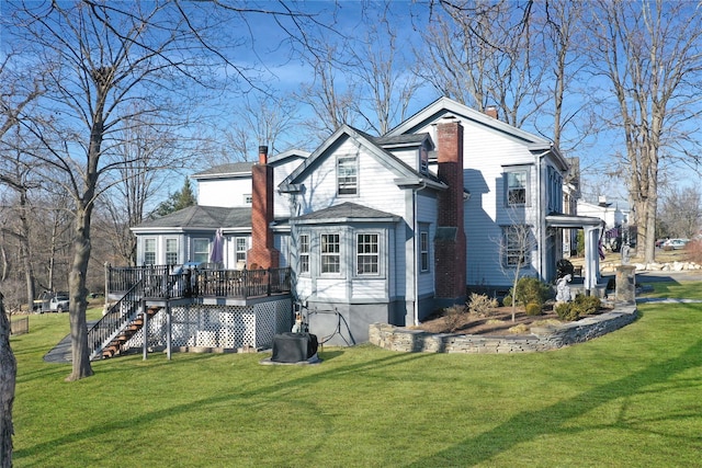 view of side of property featuring a wooden deck, stairway, a lawn, and a chimney