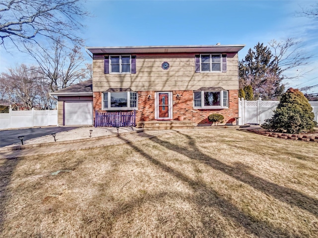 colonial home with aphalt driveway, an attached garage, fence, and brick siding