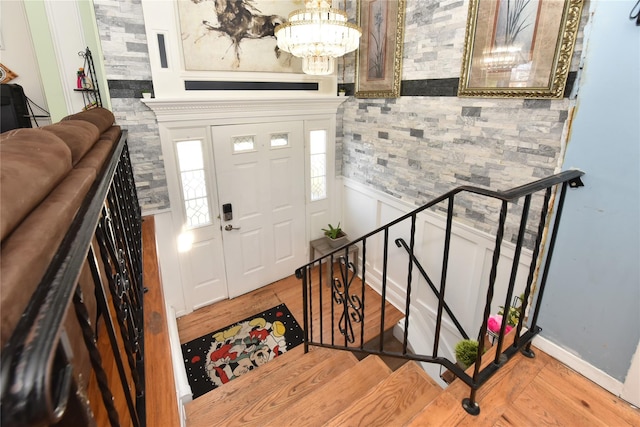 foyer entrance with a chandelier, stairway, and wood finished floors