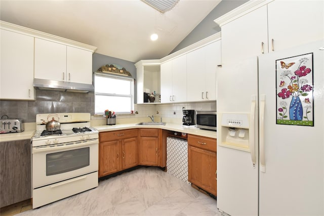 kitchen with under cabinet range hood, light countertops, lofted ceiling, white appliances, and a sink