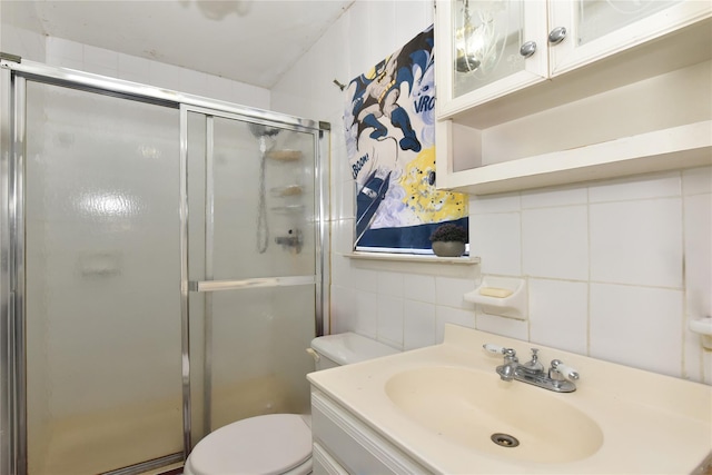 full bath with vanity, a stall shower, tile walls, toilet, and tasteful backsplash