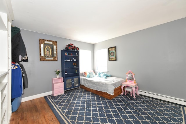 bedroom with a baseboard heating unit, baseboards, and dark wood-style floors