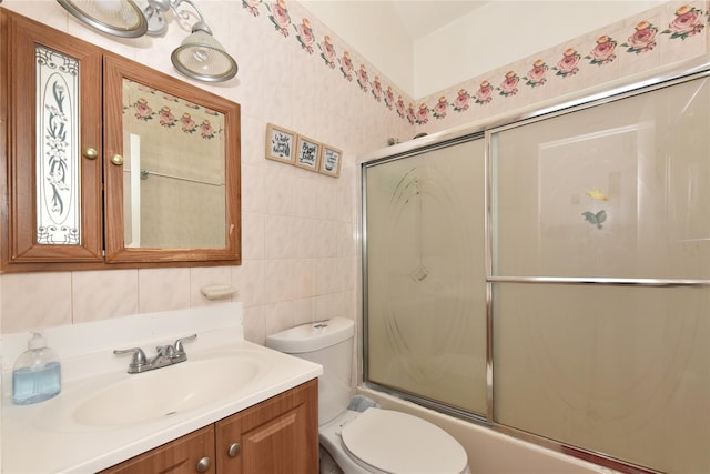 bathroom featuring tasteful backsplash, toilet, vanity, enclosed tub / shower combo, and tile walls