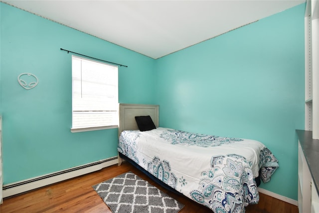 bedroom featuring wood finished floors and a baseboard radiator