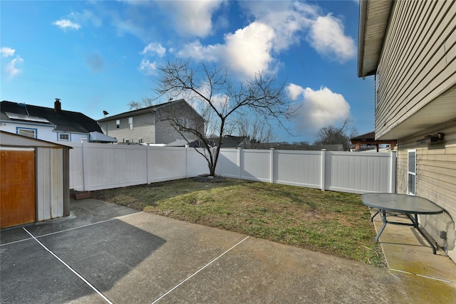 view of yard with a fenced backyard, a shed, an outbuilding, and a patio