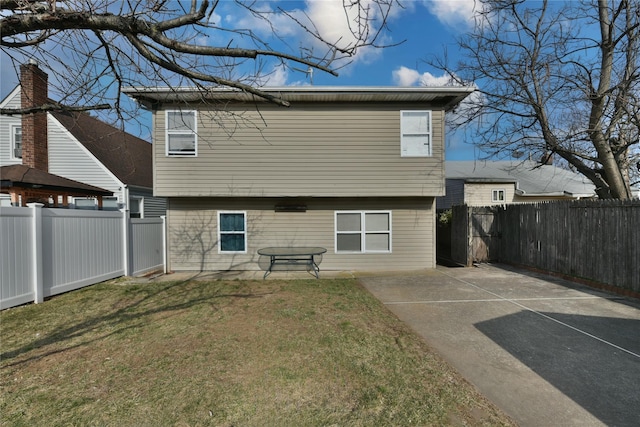 rear view of house with a patio area, a yard, and a fenced backyard