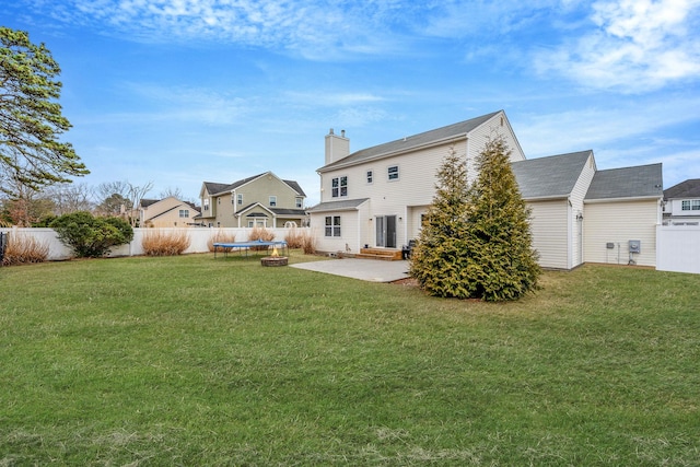 back of house featuring a yard, a fenced backyard, entry steps, and a trampoline