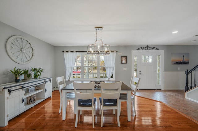 dining room with a baseboard heating unit, a chandelier, stairs, recessed lighting, and wood finished floors