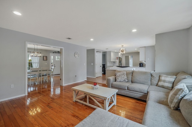 living room featuring a notable chandelier, light wood-style flooring, and visible vents