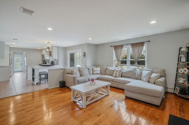 living area with light wood finished floors, visible vents, a healthy amount of sunlight, and a baseboard radiator