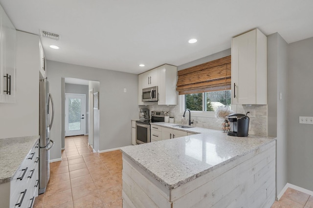 kitchen with a sink, visible vents, appliances with stainless steel finishes, and decorative backsplash