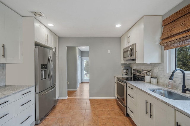 kitchen with visible vents, a sink, stainless steel appliances, white cabinets, and baseboards