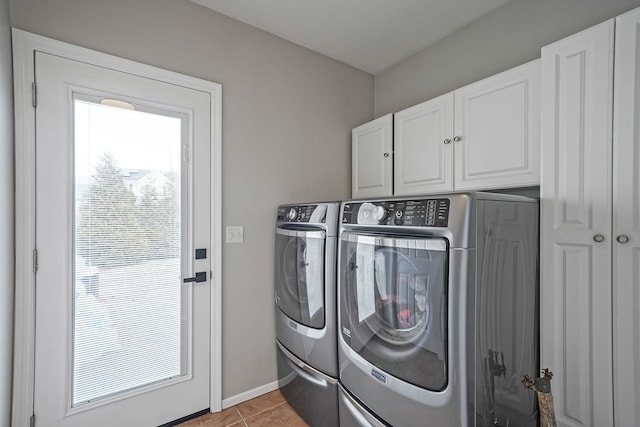 laundry area with light tile patterned flooring, washing machine and dryer, cabinet space, and baseboards