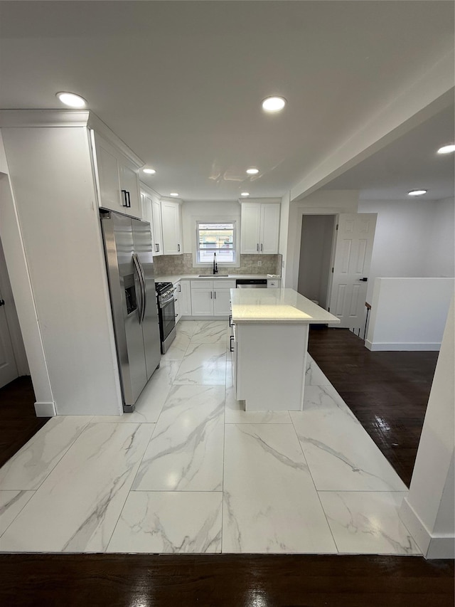 kitchen featuring a sink, tasteful backsplash, marble finish floor, and appliances with stainless steel finishes