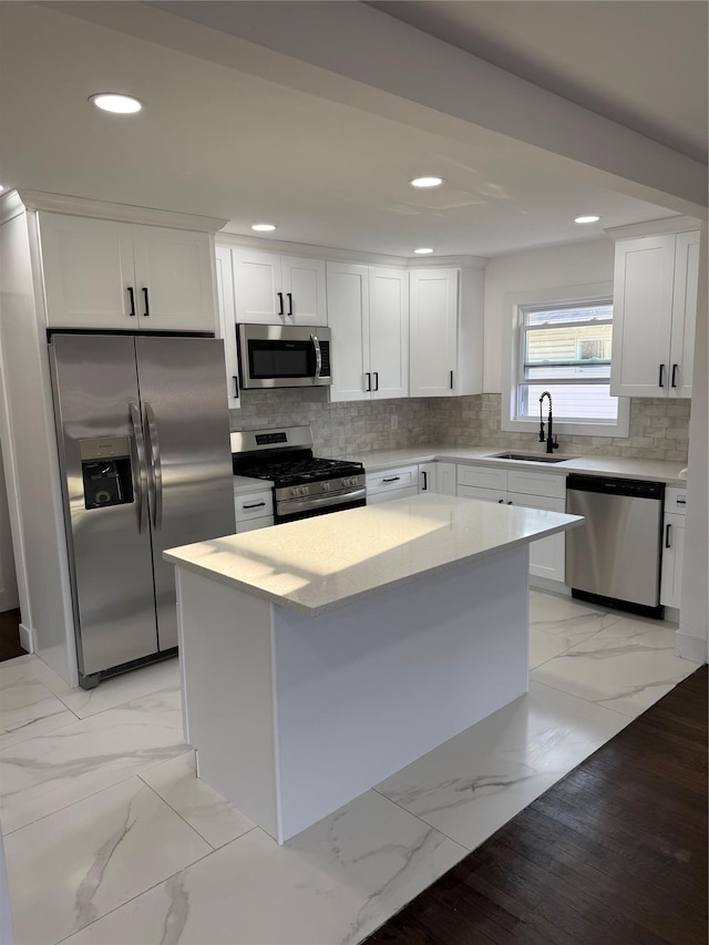 kitchen with marble finish floor, a sink, backsplash, a kitchen island, and appliances with stainless steel finishes