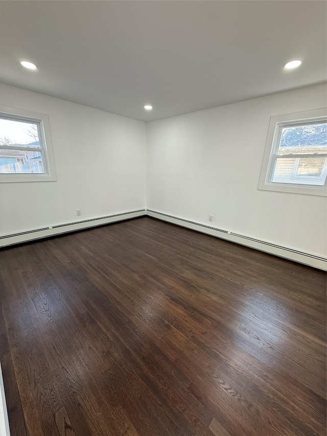 spare room with dark wood finished floors, recessed lighting, and a baseboard heating unit