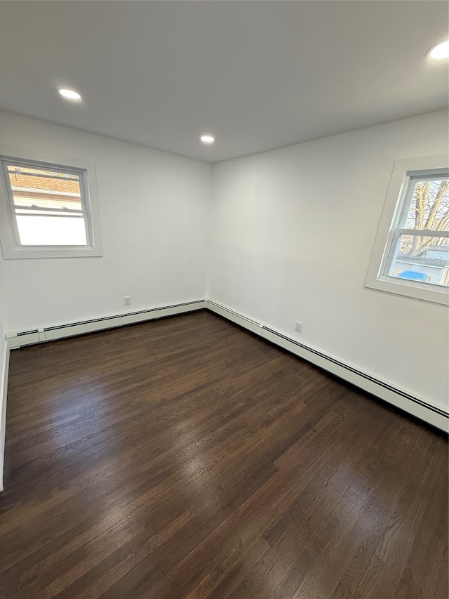 empty room featuring baseboard heating, recessed lighting, and dark wood-type flooring