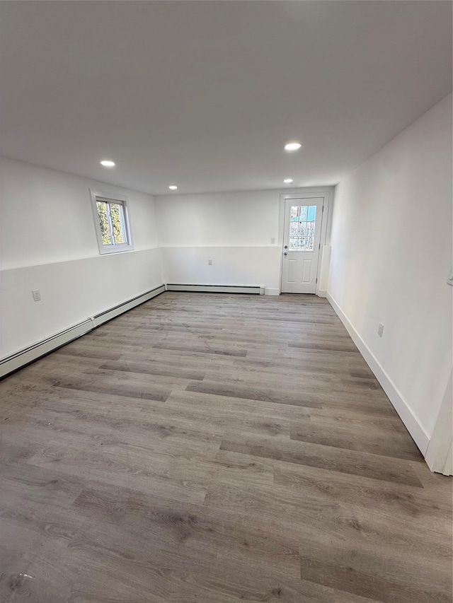 interior space featuring a baseboard heating unit, recessed lighting, wood finished floors, and baseboards