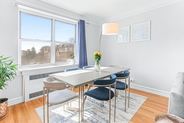 dining area with crown molding, radiator heating unit, wood finished floors, and baseboards