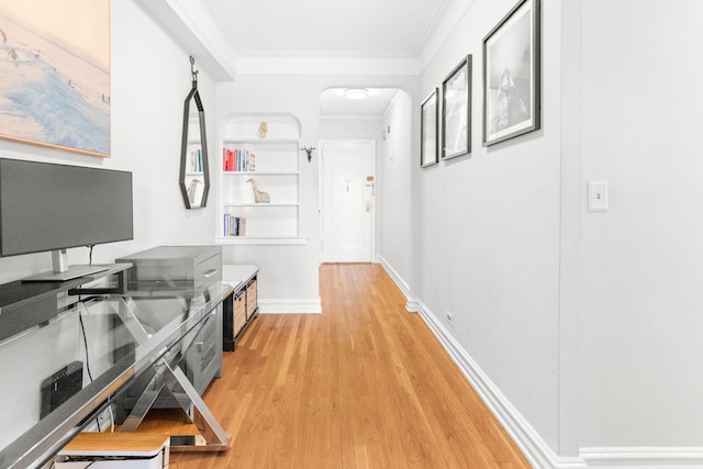 hallway with arched walkways, light wood-style flooring, crown molding, and baseboards