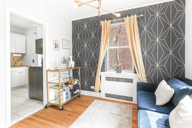 living area featuring light wood finished floors, wallpapered walls, radiator heating unit, and an accent wall