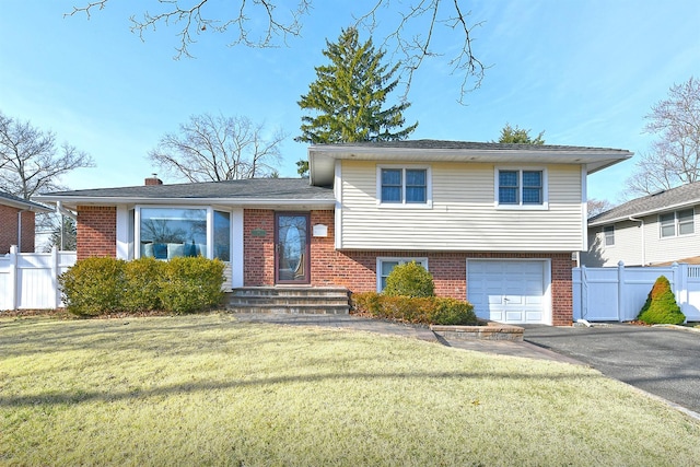 split level home featuring brick siding, a front lawn, and fence