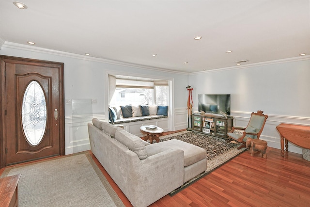 living area with visible vents, wood finished floors, wainscoting, and crown molding