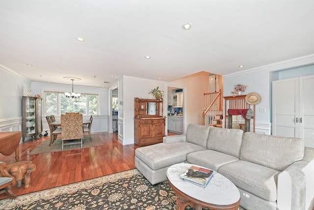 living area featuring light wood-type flooring, a wainscoted wall, ornamental molding, a chandelier, and stairs