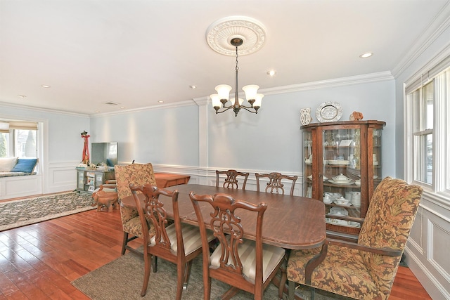 dining space with an inviting chandelier, a decorative wall, and wood finished floors