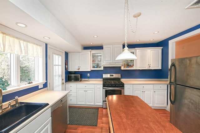 kitchen with visible vents, a sink, under cabinet range hood, wood finished floors, and stainless steel appliances